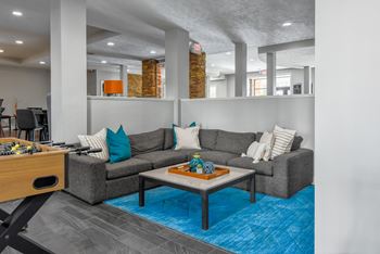 A living room with a grey couch and a blue rug.